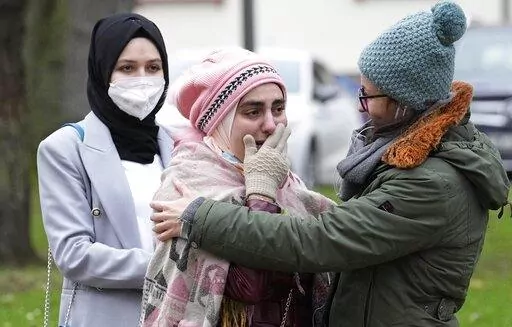 Syrian women Yasemine, center, who lost her father and brother in Syria, reacts after the verdict in front of the court in Koblenz, Germany, Thursday, Jan. 13, 2022. A German court has convicted a former Syrian secret police officer of crimes against humanity for overseeing the abuse of detainees at a jail near Damascus a decade ago. The verdict Thursday in the landmark trial has been keenly anticipated by Syrians who suffered abuse or lost relatives in the country’s long-running conflict. (AP