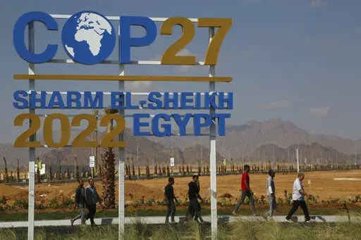 Workers walk past signage promoting this year’s United Nations global summit on climate change, known as COP27, adorns Peace Road, in Sharm el-Sheikh, South Sinai, Egypt, Wednesday, Nov. 2, 2022. As this year’s United Nations climate summit approaches, Egypt’s government is touting its efforts to make Sharm el-Sheikh a more eco-friendly tourist destination. (AP Photo/Thomas Hartwell)