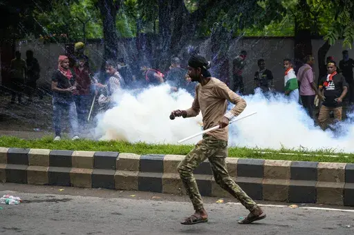 Protestors against the rape and murder of a resident doctor at a government hospital earlier this month, runs as police fire tear gas, in Kolkata, India, Tuesday, Aug. 27, 2024. (AP Photo/Bikas Das)