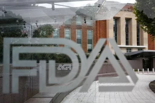 This Aug. 2, 2018 file photo shows the U.S. Food and Drug Administration building behind FDA logos at a bus stop on the agency's campus in Silver Spring, Md. The Food and Drug Administration has issued a negative review of a closely watched experimental drug for the debilitating illness known as Lou Gehrig’s disease. The review comes ahead of a meeting this week for outside experts to vote on the drug for ALS. The drug has been the focal point of a lobbying campaign by patients, their families