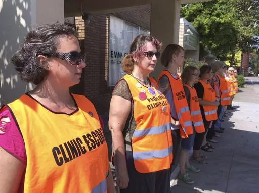 Escort volunteers line up outside the EMW Women's Surgical Center, on Monday, July 17, 2017, in Louisville, Ky. A pregnant woman in Kentucky who filed a lawsuit demanding the right to an abortion has learned her embryo no longer has cardiac activity, her attorneys said Tuesday, Dec. 12, 2023. Her attorneys didn't immediately comment on what effect the development would have on the lawsuit filed last week in a state court in Louisville. (AP Photo/Dylan Lovan, File)