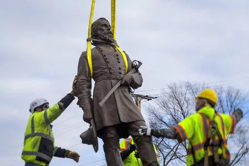 Workers begin to lay the bronze statue of Confederate General A.P. Hill onto a flatbed truck on Monday Dec. 12, 2022 in Richmond, Va. Workers are still planning to exhume the remains of General Hill which located inside the base of the statue. (AP Photo/John C. Clark)