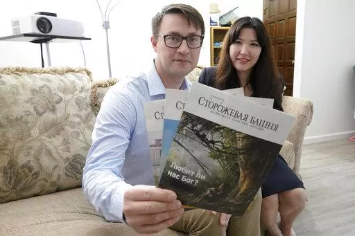 Dmitrii and Nellia Antsybor, who are from Russia and sought asylum in the United States in 2021, pose for a photo, Monday, Feb. 28, 2022, at the home where they are living in Federal Way, Wash., as they hold Jehovah's Witness Watchtower literature printed in Russian. Over the past several years, hundreds of Jehovah's Witnesses have been subjected to raids, arrests and prosecution in Russia, and many have fled to other countries hoping to find religious freedom and build new lives for themselves.