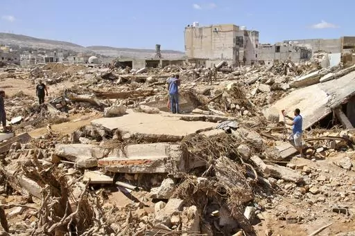 Two men hug as people look for survivors in the flooded city of Derna, Libya, Wednesday, Sept.13, 2023. For many Libyans, the disastrous flooding that killed more than 11,000 people have fostered a sense of unity. The collective grief has morphed into a rallying cry of national unity in a country blighted by 12 years of conflict and division. (AP Photo/Yousef Murad, File)