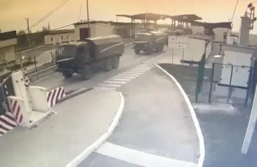 In this image made from video provided by the Border Service of Ukraine, military vehicles pass a control point at the Armyansk checkpoint at the Ukraine-Crimea border, Thursday, Feb. 24, 2022. The Ukrainian border service on Thursday released video it said showed Russian military vehicles crossing its border from Crimea. In a statement, it added that "the movement of military equipment from the peninsula is being recorded across the administrative border". (Border Service of Ukraine via AP)