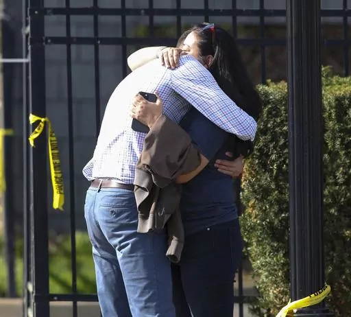 Two people embrace outside of a building where a shooting took place in Louisville, Ky., Monday, April 10, 2023. (Michael Clevenger/Courier Journal via AP)