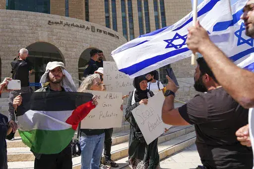 Supporters of Mohammed el-Halabi hold a Palestinian flag and placards as protesters wave Israeli flags, outside the district court in the southern Israeli city of Beersheba, Wednesday, June 15, 2022. The court found the Gaza aid worker guilty of several terrorism charges. El-Halabi, who was the Gaza director for the Christian charity World Vision from 2014 until his arrest in 2016, was accused of diverting tens of millions of dollars to the Islamic militant group Hamas that rules the territory. 