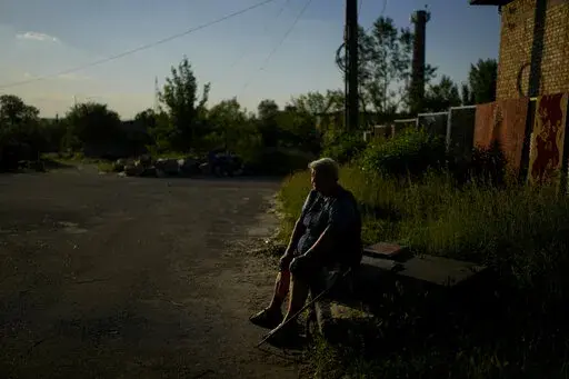 Olga Vasilyevna sits outside her home in Gorenka, on the outskirts of Kyiv,  Ukraine, Wednesday, June 8, 2022. Vasilyevna says that after attacks she still has no water nor electricity. (AP Photo/Natacha Pisarenko)