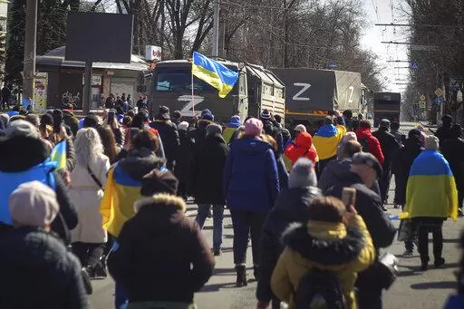 People with Ukrainian flags walk towards Russian army trucks during a rally against the Russian occupation in Kherson, Ukraine, Sunday, March 20, 2022. Ever since Russian forces took the southern Ukrainian city of Kherson in early March, residents sensed the occupiers had a special plan for their town. Now, amid a crescendo of warnings from Ukraine that Russia plans to stage a sham referendum to transform the territory into a pro-Moscow "people's republic," it appears locals guessed right. (AP P