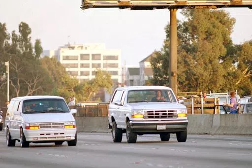 Al Cowlings, with O.J. Simpson hiding, drives a white Ford Bronco as they lead police on a two-county chase along the northbound 405 Freeway towards Simpson's home, June 17, 1994, in Los Angeles. Simpson, the decorated football superstar and Hollywood actor who was acquitted of charges he killed his former wife and her friend but later found liable in a separate civil trial, has died. He was 76. (AP Photo/Lois Bernstein, File)