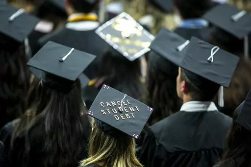 The cap of a University of Iowa graduates candidate is decorated with writing reading "Cancel student debt" during a commencement ceremony for the College of Liberal Arts and Sciences, Saturday, May 14, 2022, at Carver-Hawkeye Arena in Iowa City, Iowa. Massive tech layoffs, bank failures and a potential U.S. recession could throw a wrench in the plans of 2023 graduates — in the same year federal student loan payments are expected to resume and accrue interest. (Joseph Cress/Iowa City Press-Cit