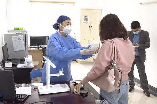 In this photo taken from video released by Shanghai Media Group, a medical worker hands over aerosolised COVID vaccine developed by Chinese biopharmaceutical company CanSino Biologics Inc. in Shanghai on Wednesday, Oct. 26, 2022. The Chinese city of Shanghai started administering the inhalable COVID-19 vaccine on Wednesday in what appears to be a world first. (Shanghai Media Group via AP)