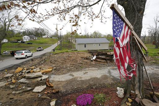 CORRECTS STATE TO KENTUCKY INSTEAD OF TENNESSEE - A flag hangs near the remains of a home destroyed in a Dec. 10 tornado on April 21, 2022, in Dawson Springs, Ky. Four months after a massive tornado tore through the state, hundreds of Kentuckians are arduously reconstructing their pre-storm existence. (AP Photo/Mark Humphrey)