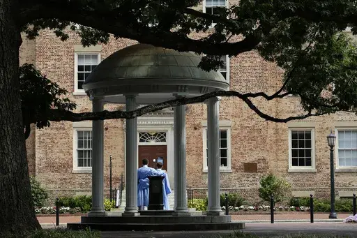 Graduates of the University of North Carolina take pictures at the Old Well on campus in Chapel Hill, N.C., June 30, 2020. (AP Photo/Gerry Broome, File)
