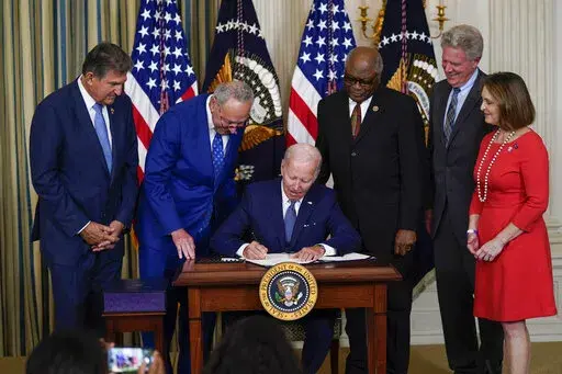 President Joe Biden signs the Democrats' landmark climate change and health care bill in the State Dining Room of the White House in Washington, Aug. 16, 2022, as from left, Sen. Joe Manchin, D-W.Va., Senate Majority Leader Chuck Schumer of N.Y., House Majority Whip Rep. James Clyburn, D-S.C., Rep. Frank Pallone, D-N.J., and Rep. Kathy Castor, D-Fla., watch. After decades of failed attempts, Democrats passed legislation that aims to reign in the soaring costs of drugs for some Americans. (AP Pho