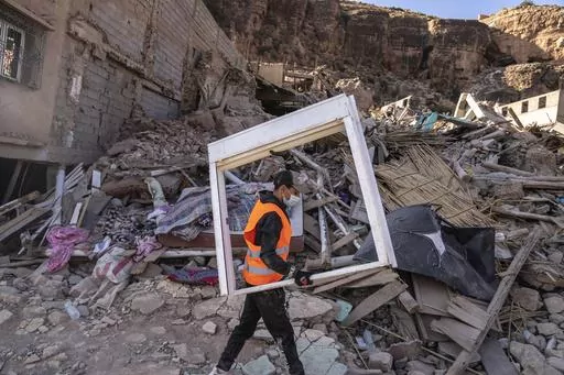 A volunteer helps salvage furniture from homes which were damaged by the earthquake, in the town of Imi N'tala, outside Marrakech, Morocco, Wednesday, Sept. 13, 2023. An aftershock rattled central Morocco on Wednesday, striking fear into rescue crews at work in High Atlas villages, digging people out from rubble that could slide. (AP Photo/Mosa'ab Elshamy)
