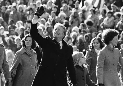 U.S. President Jimmy Carter waves to the crowd while walking with his wife, Rosalynn, and their daughter, Amy, along Pennsylvania Avenue. The Carters elected to walk the parade route from the Capitol to the White House following his inauguration in Washington, Jan. 20, 1977. Carter announced his campaign for the presidency in December 1974. At that point he had never met an American president. He later said part of what nudged him into the race was meeting several candidates ahead of the 1972 ca