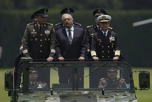 Mexico's President Andres Manuel Lopez Obrador, center, Defense Secretary Luis Cresencio Sandoval, left, and Naval Commander Jose Rafael Ojeda ride in a military vehicle during a parade introducing the new army commander, in Mexico City, Aug. 13, 2021. Mexico launched its army-run airline on Dec. 26, 2023, another role that López Obrador has given to Mexico’s armed forces. (AP Photo/Fernando Llano, File)