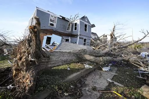 An overturned tree sits in front of a tornado damaged home in Mayfield, Ky., on Dec. 11, 2021. On Friday, March 17, 2023, The Associated Press reported on stories circulating online incorrectly claiming climate, weather or meteorological events that we would classify as “extreme” have declined in severity over the last 20 or 30 years. (AP Photo/Mark Humphrey, File)