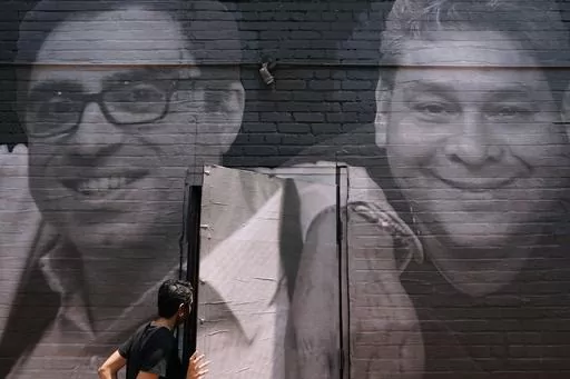 A woman steps through a door that is covered by a mural depicting American hostages and wrongful detainees who are being held abroad, Wednesday, July 20, 2022, in the Georgetown neighborhood of Washington. At left is Siamak Namazi, who has been in captivity in Iran since 2015. At right is Jose Angel Pereira, who has been imprisoned in Venezuela since 2017. Iran has transferred five Iranian-Americans from prison, identifying three of the prisoners as Siamak Namazi, Emad Shargi, and Morad Tahbaz, 