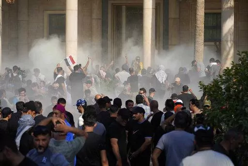 Iraqi security forces fire tear gas on the followers of Shiite cleric Muqtada al-Sadr inside the government Palace, Baghdad, Iraq, Monday, Aug. 29, 2022. Al-Sadr, a hugely influential Shiite cleric announced he will resign from Iraqi politics and his angry followers stormed the government palace in response. The chaos Monday sparked fears that violence could erupt in a country already beset by its worst political crisis in years. (AP Photo/Hadi Mizban)