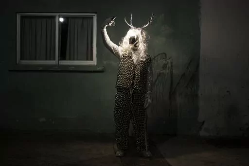 A man poses for a photo wearing a costume during a Muerteada parade in San Agustin Etla, Thursday, Nov. 2, 2023. Mexicans in the Oaxacan town celebrate the traditional Muerteada, a theatrical recreation that is performed through the night of November 1 until the early morning of the following day, with dances and music parading through the streets, while telling the story of how a deceased person is resurrected with the help of a priest, a doctor and a spiritist. (AP Photo/Maria Alferez)