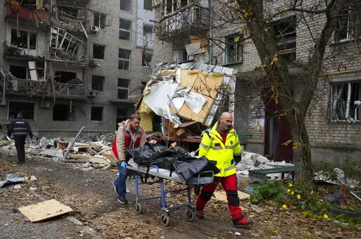 Medics carry the lifeless body of a victim found under rubble at the scene of night shelling in Mykolaiv, Ukraine, Friday, Nov. 11, 2022. (AP Photo/Efrem Lukatsky)