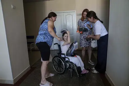 Oksana Femeniuk, left, and her daughter Solomiia, receive presents from volunteers, a day after they survived a Russian missile strike on Okhmatdyt children's hospital, in Kyiv, Ukraine, Tuesday, July 9, 2024. The toll of Russia’s heaviest bombardment of Kyiv in almost four months — one of the deadliest of the war — shows the devastating human cost of Russia’s improved targeting tactics. (AP Photo/Evgeniy Maloletka)