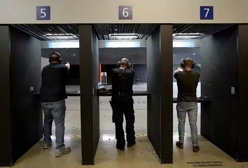 Gun owners fire their pistols at an indoor shooting range during a qualification course to renew their carry concealed handgun permits, July 1, 2022, at the Placer Sporting Club in Roseville, Calif. A new California law that bans people from carrying firearms in most public places is once again blocked from taking effect as a court case challenging the law continues. A 9th Circuit Court of Appeals panel on Saturday, Jan. 6, 2024, dissolved a temporary hold on a lower court injunction blocking th