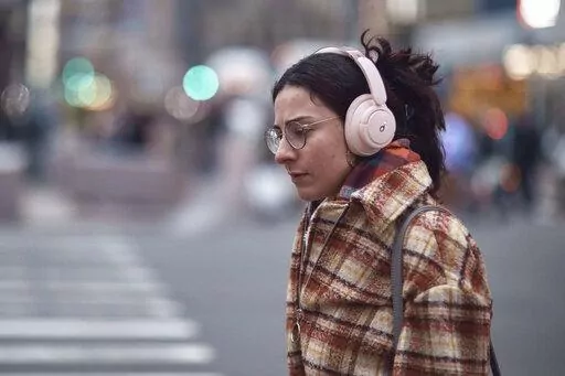 A woman walks using her headphones on Tuesday, Jan. 17, 2023, in New York. After the relative quiet of the pandemic, New York City has come roaring back. Just listen: Jackhammers disrupt the peace and fleets of honking cars, trucks and buses again clog thoroughfares as millions of denizens return to the streets — their voices and clacking heels adding to the ear-splitting din. In one of the world's noisiest cities, the cacophony has returned louder than ever. (AP Photo/Andres Kudacki)
