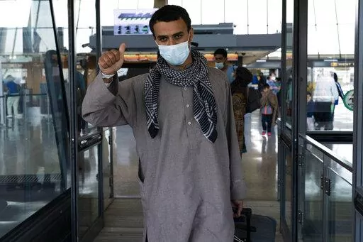 Families evacuated from Kabul, Afghanistan, walk through the terminal before boarding a bus after they arrived at Washington Dulles International Airport, in Chantilly, Va., on Friday, Aug. 27, 2021. (AP Photo/Jose Luis Magana)