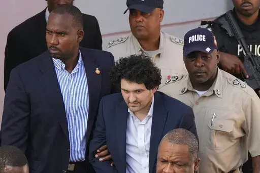 FTX founder Sam Bankman-Fried, center, is escorted out of Magistrate Court into a Corrections van, following a hearing in Nassau, Bahamas, Monday, Dec. 19, 2022. (AP Photo/Rebecca Blackwell)