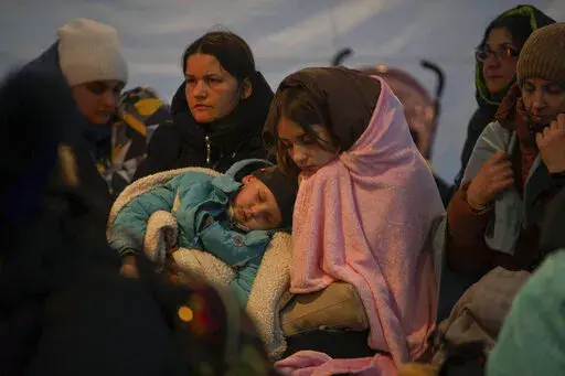 Refugees, mostly women with children, rest inside a tent after arriving at the border crossing, in Medyka, Poland on Sunday, March 6, 2022. (AP Photo/Visar Kryeziu)