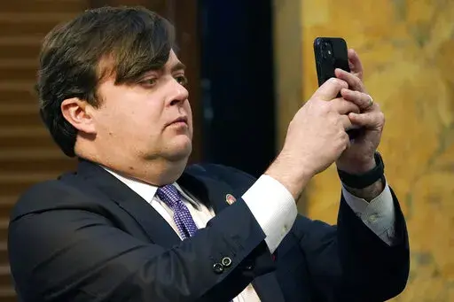 Rep. Nick Bain, R-Corinth, uses his cell phone to take a photograph of the lawmakers in the House chamber at the Mississippi State Capitol in Jackson, Miss., Tuesday, Feb. 8, 2022. Lawmakers in both chambers have a Thursday deadline for original floor action on general bills and constitutional amendments originating in their own House. (AP Photo/Rogelio V. Solis)