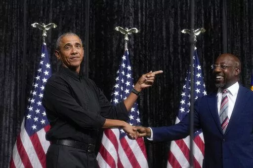 Former President Barack Obama, left, greets Sen. Raphael Warnock, D-Ga., right, before Obama speaks during a rally on Thursday, Dec. 1, 2022, in Atlanta. Warnock is running against Republican Herschel Walker in a runoff election. (AP Photo/Brynn Anderson)