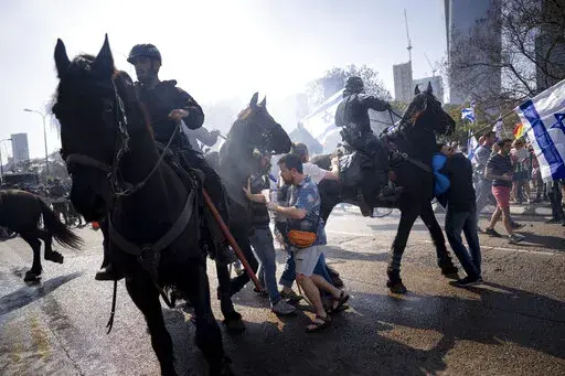 Israeli police deploy horses and stun grenades to disperse Israelis blocking a main road during a protest against plans by Prime Minister Benjamin Netanyahu's new government to overhaul the judicial system, in Tel Aviv, Israel, Wednesday, March 1, 2023. (AP Photo/Oded Balilty)