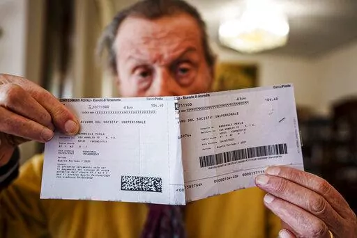 Luigi Boni, a 95-year-old Florentine retiree, shows the latest water bill in his house during an interview with The Associated Press in Florence, Italy, Thursday, Feb. 17, 2022. Boni said that he can't cope with the more than 50% hike in water, gas and electricity bills this winter. Boni was included in a relief program 'Adopt a bill' that collects and redistributes donations from wealthier fellow citizens to help pay the utility bills of those elderly people in need. (AP Photo/Domenico Stinelli