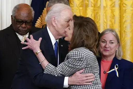 President Joe Biden kisses House Speaker Nancy Pelosi of Calif., during an Affordable Care Act event in the East Room of the White House in Washington, Tuesday, April 5, 2022. At left is House Majority Whip James Clyburn, D-S.C., and right is Rep. Susan Wild, D-Pa. Pelosi has tested positive for COVID-19 and is currently asymptomatic, her spokesman Drew Hammill said in a tweet Thursday, April 7. (AP Photo/Carolyn Kaster)