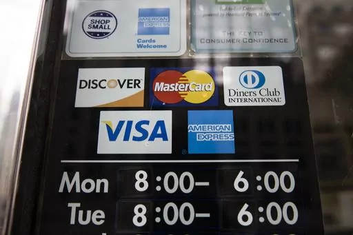 Credit card options are shown on a store's door on Nov. 29, 2018 in Philadelphia. Noticeable pockets of Americans are quickly running up their credit card balances and increasing numbers are now falling behind on their debts. (AP Photo/Matt Rourke, File)