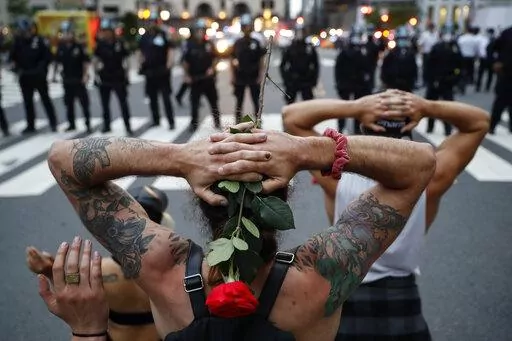 Protesters kneel in front of New York City Police Department officers before being arrested for violating curfew beside the iconic Plaza Hotel on 59th Street, Wednesday, June 3, 2020, in New York. Protests continued following the death of George Floyd, who died after being restrained by Minneapolis police officers on May 25. (AP Photo/John Minchillo, File)