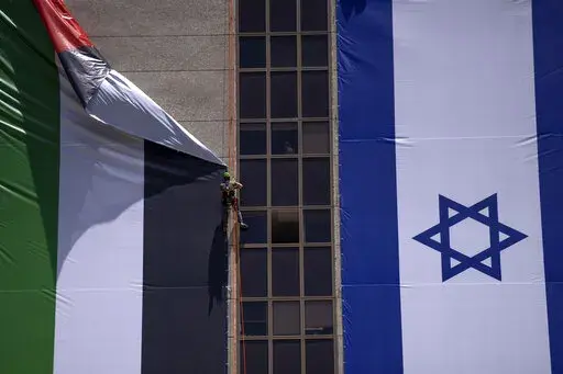 A Palestinian flag is removed from a building by Israeli authorities after being put up by an advocacy group that promotes coexistence between Palestinians and Israelis, in Ramat Gan, Israel, Wednesday, June 1, 2022. In recent weeks, Israeli authorities have gone out of their way to challenge the hoisting of the Palestinian flag. Palestinian citizens of Israel see the campaign against the flag as another affront to their national identity and their rights as a minority in the majority Jewish sta