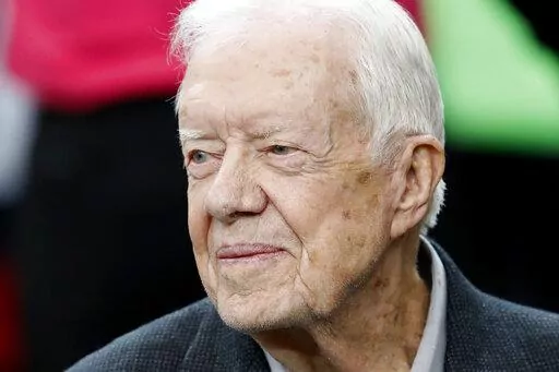 Former President Jimmy Carter sits on the Atlanta Falcons bench before the first half of an NFL football game between the Atlanta Falcons and the San Diego Chargers, Oct. 23, 2016, in Atlanta. Carter has entered home hospice care after a series of short hospital stays. The Carter Center said in a statement Saturday, Feb. 18, 2023, that Carter, 98, “decided to spend his remaining time at home with his family and receive hospice care instead of additional medical intervention.” (AP Photo/John 