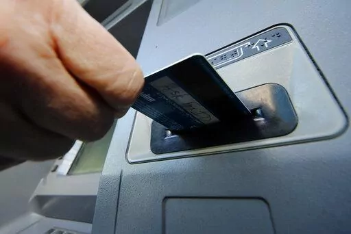 In this Saturday, Jan. 5, 2013 file photo, a person inserts a debit card into an ATM in Pittsburgh. Whether you’re a customer who is coming to or leaving a bank, mergers and acquisitions are a good time to evaluate your banking needs.   (AP Photo/Gene J. Puskar, File)