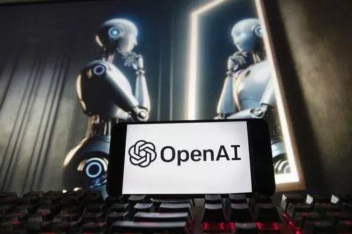 The OpenAI logo is seen displayed on a cell phone with an image on a computer monitor generated by ChatGPT's Dall-E text-to-image model, Friday, Dec. 8, 2023, in Boston. A former OpenAI leader who resigned from the company earlier this week said on Friday that product safety has "taken a backseat to shiny products" at the influential artificial intelligence company. (AP Photo/Michael Dwyer, file)