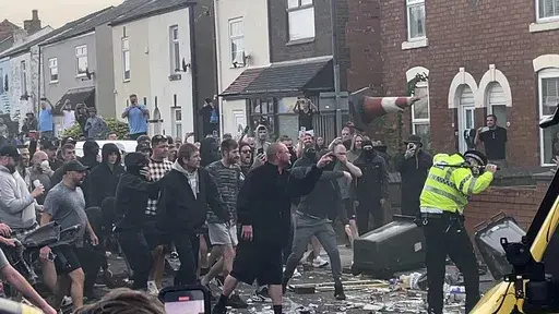 An unruly crowd clash with police, Tuesday, July 30, 2024, in Southport, northwest England, near where three girls were stabbed to death in a dance class the day before. The violence erupted shortly after a peaceful vigil was attended by hundreds in the center of Southport to mourn the 13 victims of the stabbings, including seven still in critical condition. (Richard McCarthy/PA via AP)