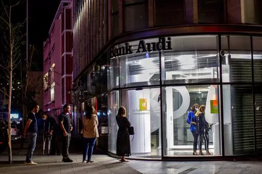 Clients wait to use ATMs outside a closed bank in Beirut, Lebanon, Wednesday, June 2, 2021. Four years into Lebanon's historic economic meltdown, Lebanon's elites are pushing an economic recovery plan that would sidestep critical reforms demanded by the International Monetary Fund. (AP Photo/Hassan Ammar, File)