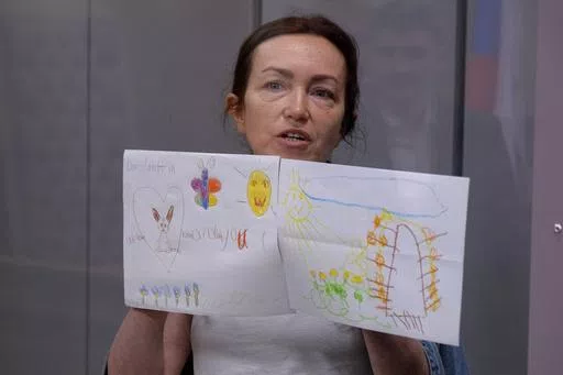 Alsu Kurmasheva, an editor for the U.S. government-funded Radio Free Europe/Radio Liberty's Tatar-Bashkir service, holds child's drawings during a court hearing in Kazan, Russia on Friday, May 31, 2024. A court in Russia on Friday ordered a detained Russian American journalist to be held until at least Aug. 5, pending investigation and trial, a further step in the Kremlin's crackdown on dissent and free speech. (AP Photo)