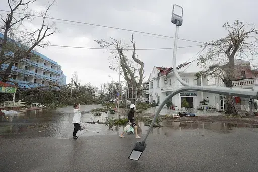 People walk past broken light post after typhoon Yagi hit the city, in Hai Phong, northern Vietnam on Sunday, Sept. 8, 2024. (Minh Quyet/VNA via AP)
