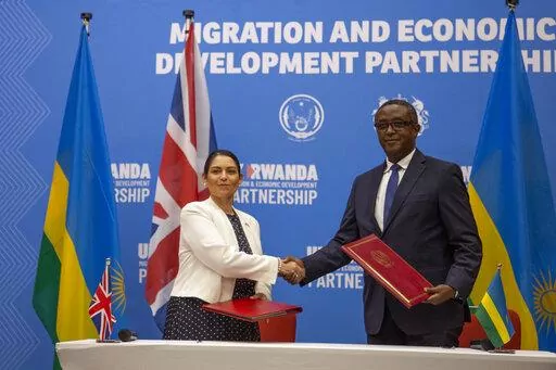 Britain's Home Secretary Priti Patel, left, shakes hands with Rwanda's Minister of Foreign Affairs Vincent Biruta, right, after signing what the two countries called an "economic development partnership" in Kigali, Rwanda Thursday, April 14, 2022. Britain's Conservative government has struck a deal to send some asylum-seekers thousands of miles away to Rwanda, a move that British opposition politicians and refugee groups condemned as inhumane, unworkable and a waste of public money. (AP Photo/Mu