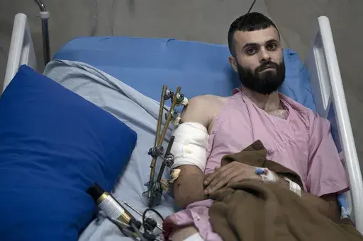 Mujahid Abadi, 24, poses for a portrait at the Ibn Sina Specialized Hospital where he is recovering from gunshot wounds and burns in the West Bank city of Jenin, Tuesday, June 25, 2024. When the Palestinian man stepped outside to see if Israeli forces had entered his uncle's neighborhood, he was shot in the arm and the foot. That was only the start of his ordeal. Hours later, beaten and bloodied, he found himself strapped to the searing hood of an Israeli military jeep driving down a road. (AP P